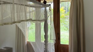 Un dormitorio con cama, una ventana con cortinas y una puerta que da al exterior.