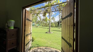 Una puerta de madera abierta que da a un césped cuidado con una palmera y un sendero de piedra.
