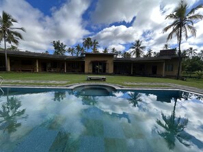 A pool area with a clear view of the surrounding buildings and palm trees. - Rivendell Twisted Tree (Kanawa)