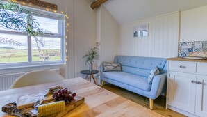 Una habitación acogedora con una mesa de madera, un sofá azul y vistas al exterior a través de una ventana.