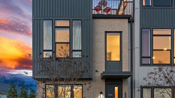 Une maison moderne à deux étages, dotée d’un balcon, de grandes fenêtres et d’un jardin bien entretenu.