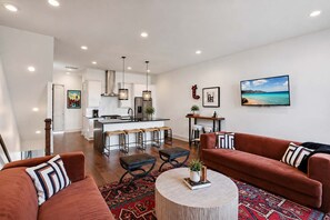 A modern living room with a red sofa, a round coffee table, and a kitchen area in the background.