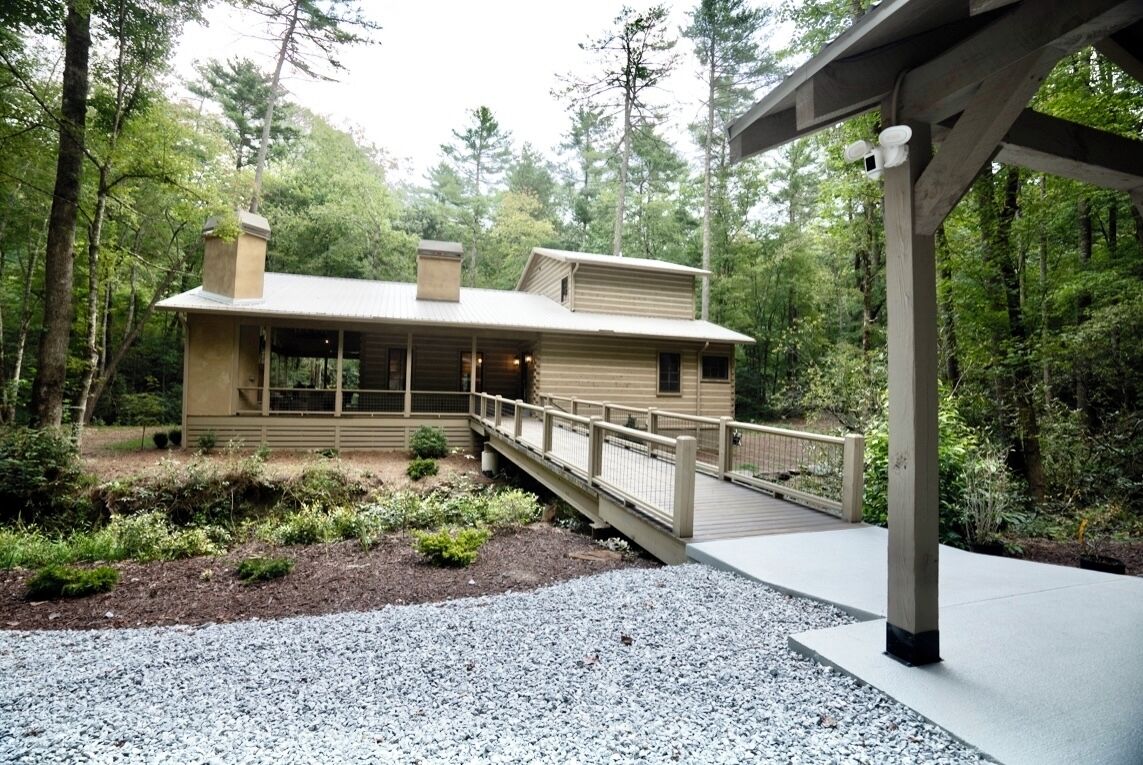 A lodge with a covered porch, a wooden deck, and a gravel pathway.