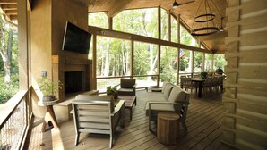 A log cabin with a wooden deck, a fireplace, a television, and outdoor seating. - Highlands Cabin on Big Creek in Horse Cove. (Highlands)