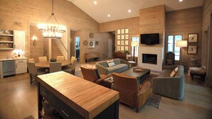 A spacious living area with a wooden ceiling, a dining table, sofas, and a fireplace. - Highlands Cabin on Big Creek in Horse Cove. (Highlands)