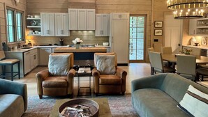 A spacious living room with leather sofas, a coffee table, and a fireplace. - Highlands Cabin on Big Creek in Horse Cove. (Highlands)