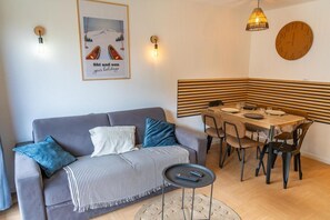 A modern living room with a grey sofa, striped throw, and a dining area with a wooden table and chairs.