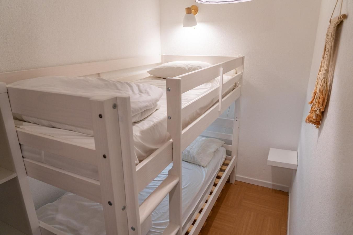 Una cama litera con escritorio abatible y una pequeña mesita de noche.