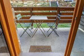 A patio area with a wooden fence, a concrete floor, and a small table with two chairs.