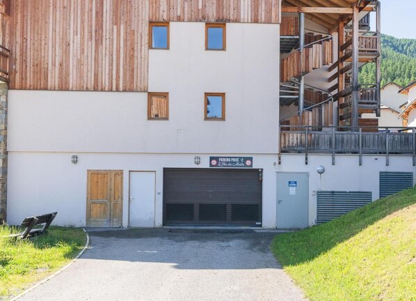 A building with a wooden facade, a garage door, and a staircase leading to a balcony.