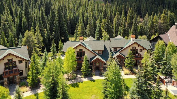 A cluster of log cabin-style buildings surrounded by dense forest, with a clear view of the surrounding mountainous landscape. - Luxurious Town Home, Short Walk to Lifts, Private Hot Tub 164B (Copper Mountain)