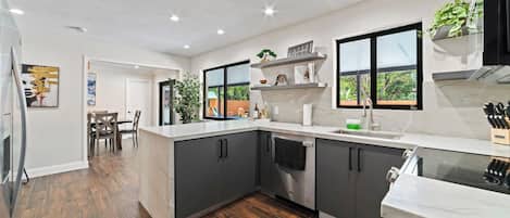 Una cocina moderna con armarios oscuros, encimera blanca y horno empotrado.