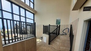 A spacious indoor area with a wooden floor, a metal railing, and a sign indicating a game room. - Beachfront Resort Condo with Pools (Orange Beach)