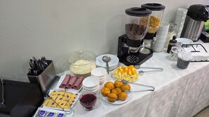 Een buffet met diverse soorten eten, zoals ontbijtgranen, fruit en gebak.
