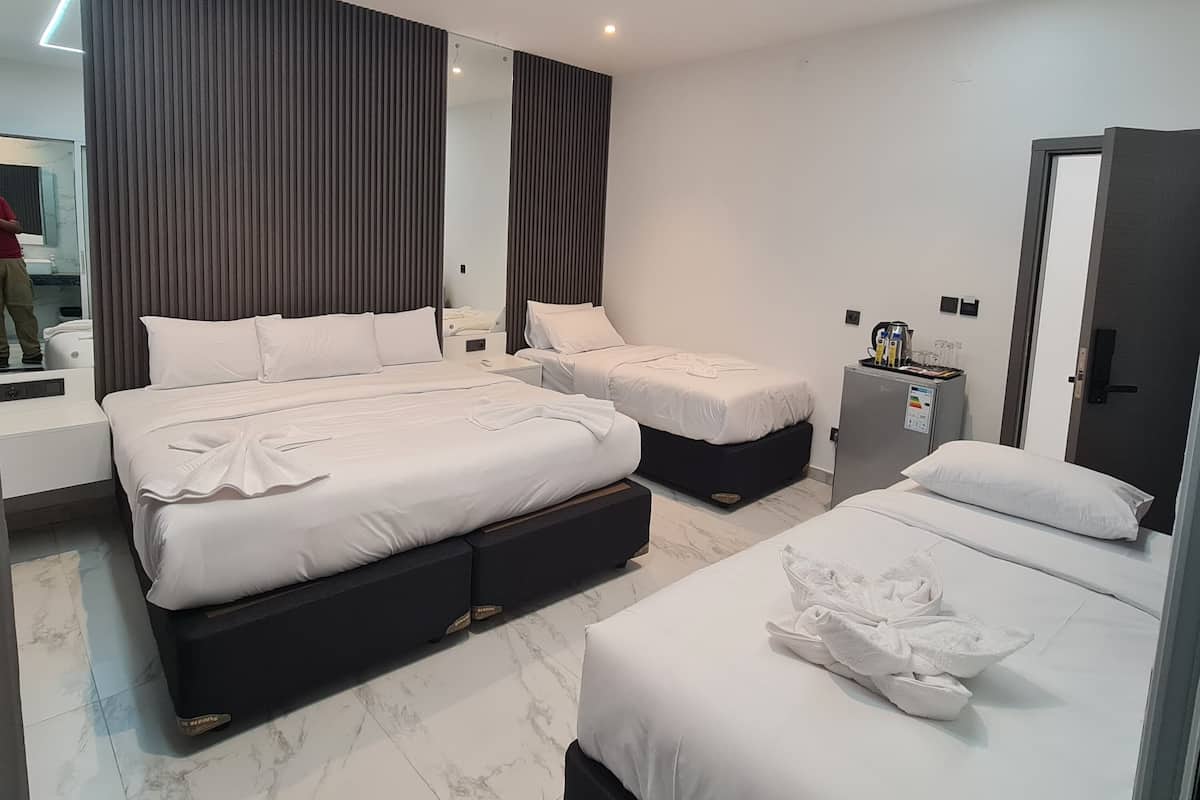 A modern hotel room with two beds, a large mirror, and a minibar.