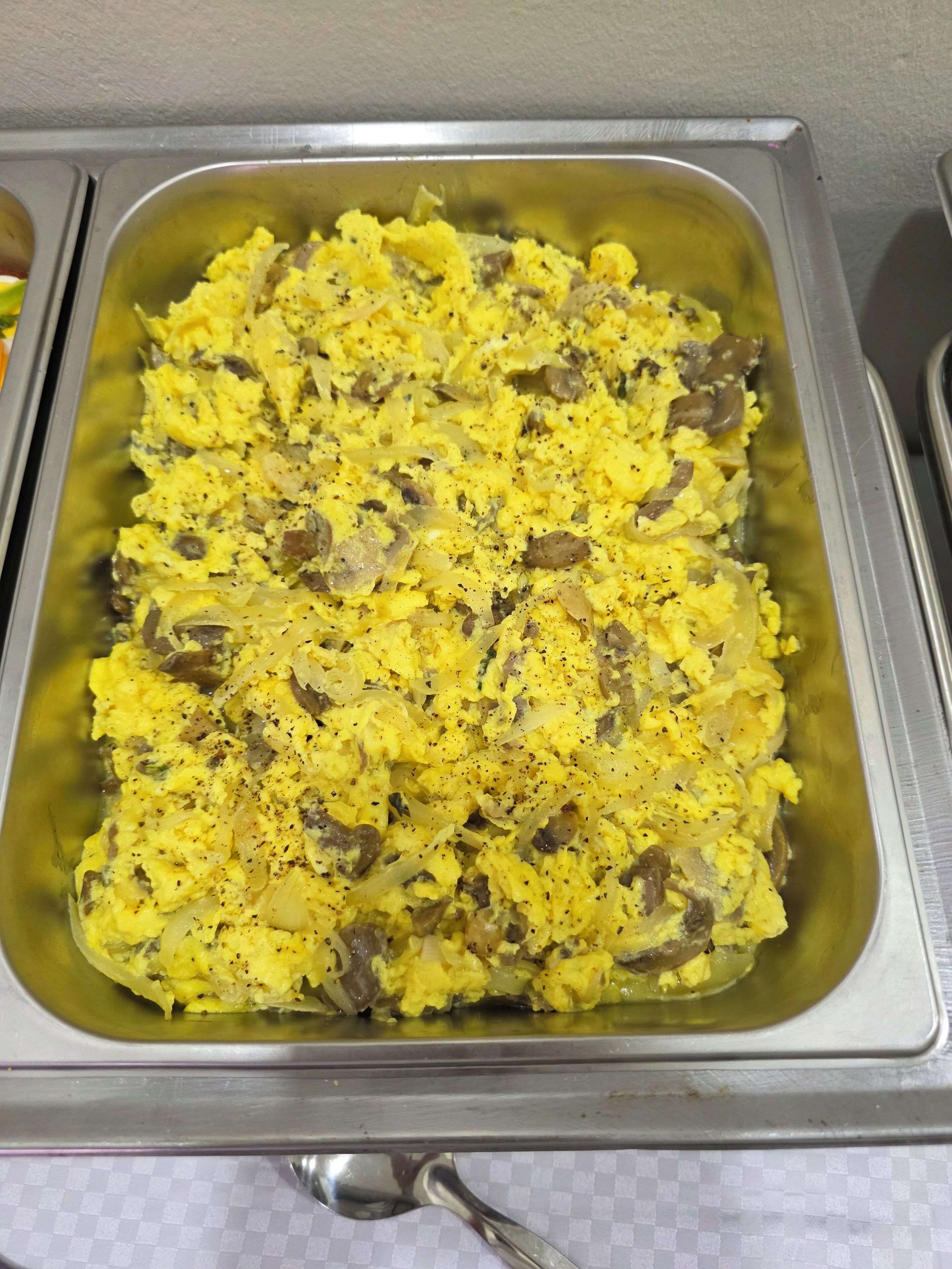 A buffet tray with scrambled eggs and mushrooms.
