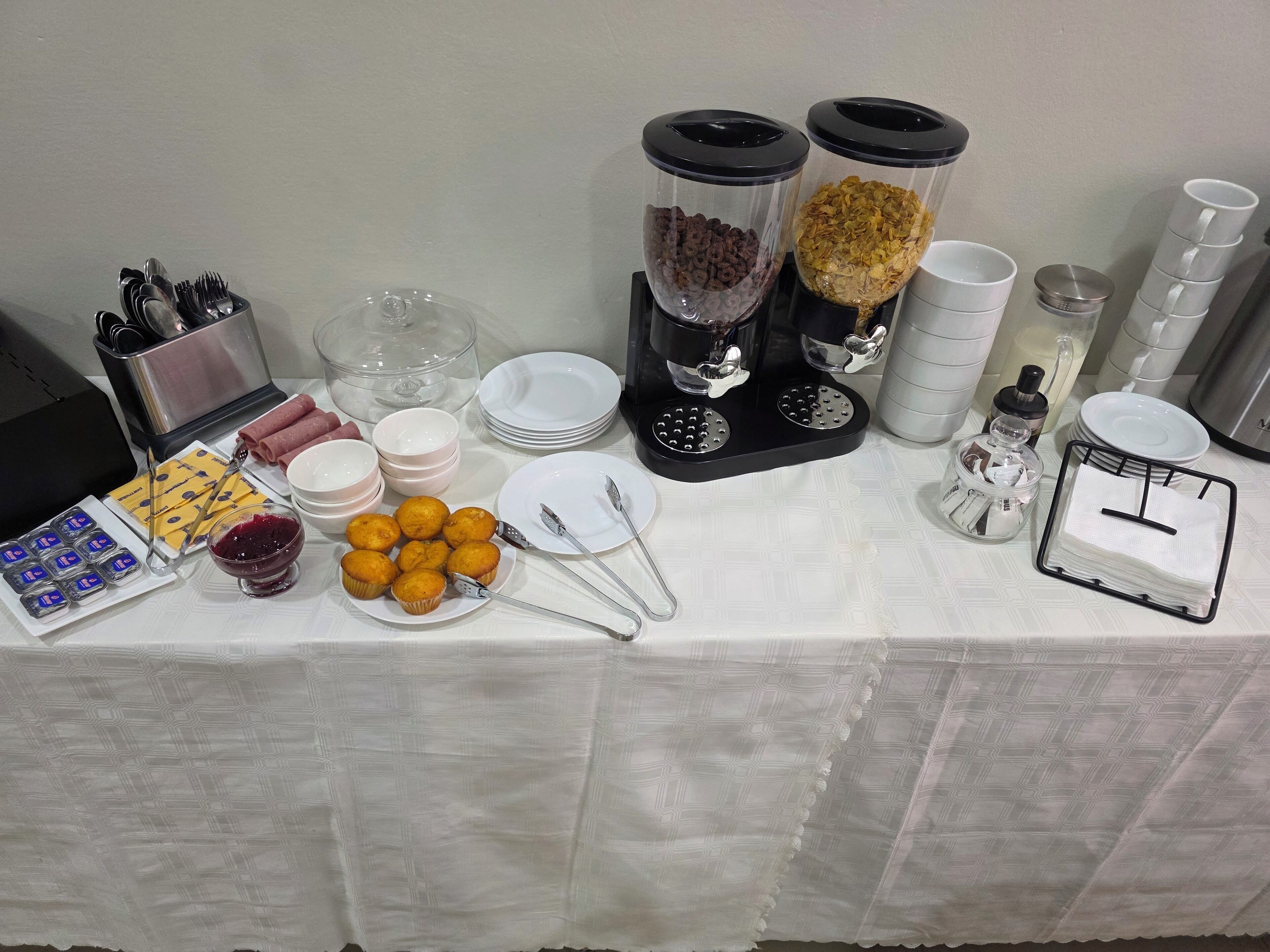 Montaje de bufé con diversos alimentos, utensilios y recipientes.