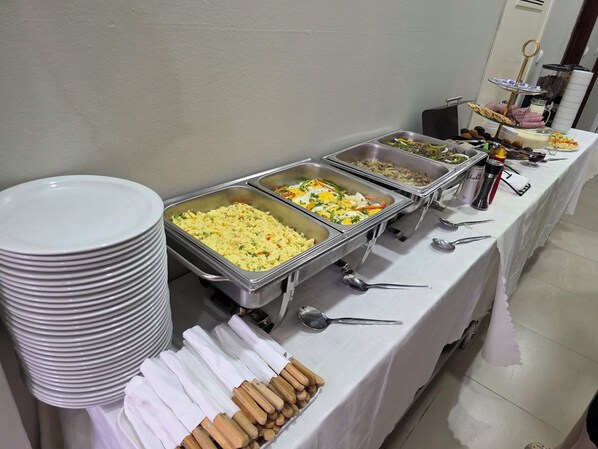 Montaje de bufé con múltiples estaciones de comida, que incluye una variedad de platos y cubiertos.