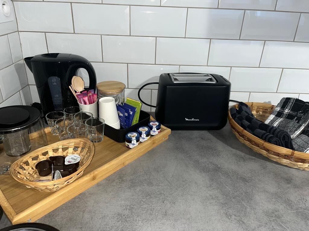 Un plan de travail de cuisine avec une machine à café, un grille-pain et divers ustensiles de cuisine.