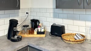 Een moderne keuken met donkere kastjes, een koffiezetapparaat, een broodrooster en een mand op het aanrecht.