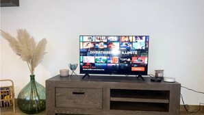 Een flatscreen televisie op een houten tv-meubel, met een Netflix logo en een knop voor een gratis proefperiode.