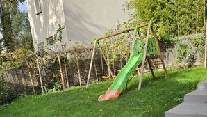 Een gazon met een groene glijbaan en een betonnen trap.