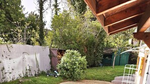 Een terras met een grindoppervlak, een bakstenen rand en een houten pergola.