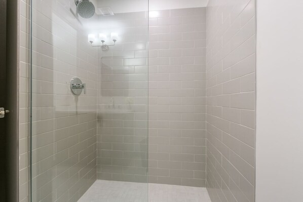 Un pequeño espacio de ducha cerrado con paredes de azulejos blancos y una puerta de cristal.