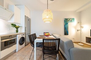 A compact kitchen with modern appliances, a dining area with a table and chairs, and a living area with a sofa.
