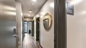 Un pasillo con piso de madera, una puerta con cerradura electrónica y un espejo redondo en la pared, y un letrero que indica la habitación 403.
