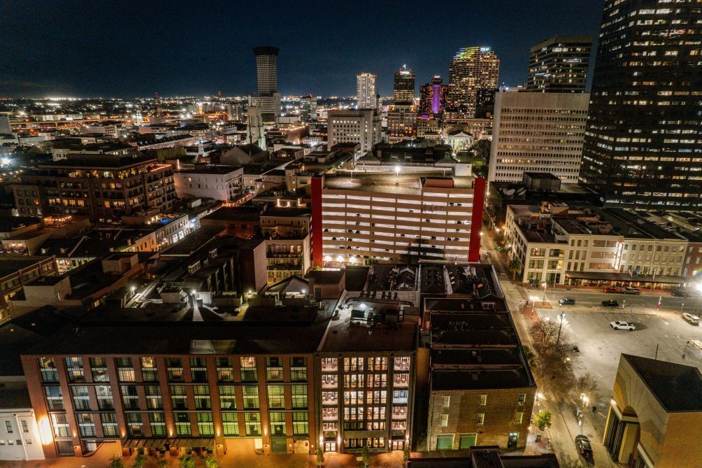 A nighttime cityscape with a prominent building featuring a red-lit parking structure.