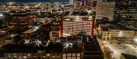A nighttime cityscape with a prominent building featuring a red-lit parking structure.