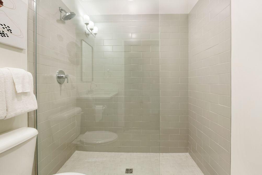 A small, modern bathroom with a glass shower enclosure, a toilet, and a sink.