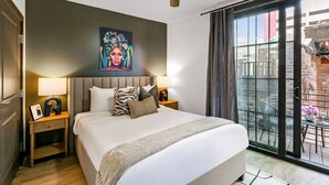 Habitación de hotel moderna con una cama grande, un ventilador de techo, un cuadro en la pared y vistas al balcón exterior.