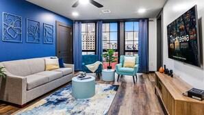 A modern living room with a sofa, two armchairs, a coffee table, and a TV.