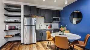 A modern kitchen with dark cabinets, stainless steel appliances, and a round table with chairs.
