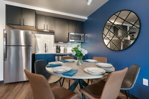 A modern kitchen with dark cabinets, stainless steel appliances, and a blue accent wall.