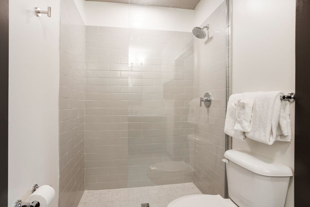 Une salle de bain moderne dotée d’une douche à parois de verre, de toilettes et d’un porte-serviettes.