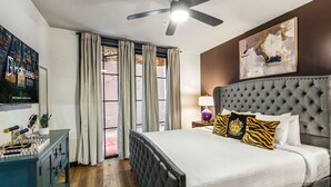 Ein Hotelzimmer mit einem großen Bett, einem Deckenventilator, einem Fenster mit Vorhängen und einem Wandbild.