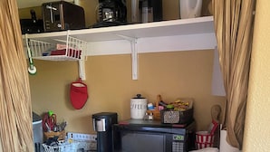 A compact kitchen with a built-in microwave, coffee maker, and a small refrigerator.