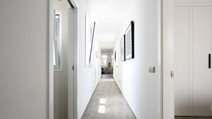 A long, narrow hallway with white walls, a wooden floor, and framed artwork on the walls. - 'kolding' Apt. - Pleasant, Cozy & Comfortable - Deluxe Apartment (Las Palmas de Gran Canaria)