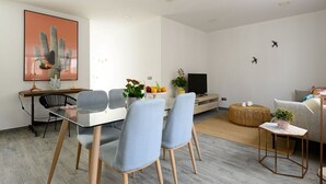A modern living room with a dining area, a flat-screen TV, and a cactus artwork on the wall. - 'kolding' Apt. - Pleasant, Cozy & Comfortable - Deluxe Apartment (Las Palmas de Gran Canaria)
