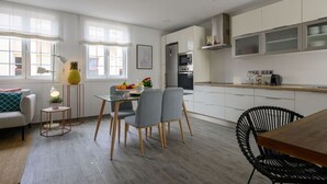 A modern kitchen with white cabinets, a dining area with a glass table, and a cozy seating area with a sofa and a lamp. - 'kolding' Apt. - Pleasant, Cozy & Comfortable - Deluxe Apartment (Las Palmas de Gran Canaria)