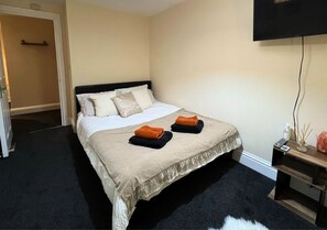 Relax in comfort with a neatly made bed, a convenient nightstand, and a flat-screen TV.