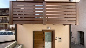 A modern building entrance with a wooden gate, a glass door, and a small step leading to the entrance. - House at the Alley [near Lake Garda] (Vigo)