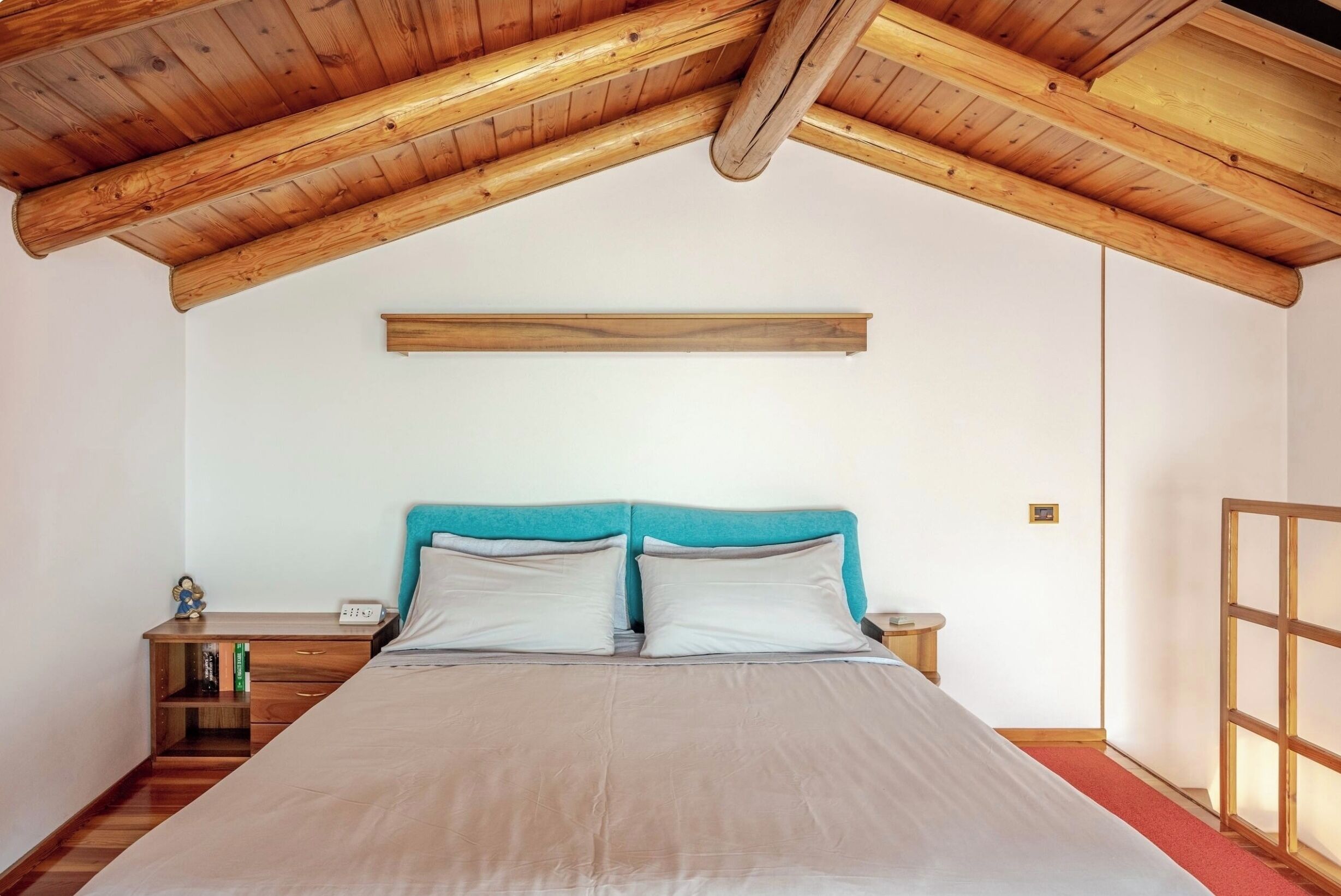 Ein Schlafzimmer mit Holzboden, einem Bett mit zwei Kissen, einem Nachttisch und einem kleinen Tisch.