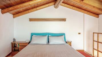 Ein Schlafzimmer mit Holzboden, einem Bett mit zwei Kissen, einem Nachttisch und einem kleinen Tisch.