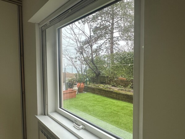 Una ventana con vista a un jardín y árboles.