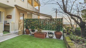 A residential building with a balcony, a wooden gate, and a well-maintained lawn with potted plants. - B&B Trieste Sea Life (Trieste)