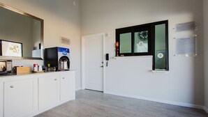Una cocina moderna con armarios blancos, microondas empotrado y cafetera en la encimera.